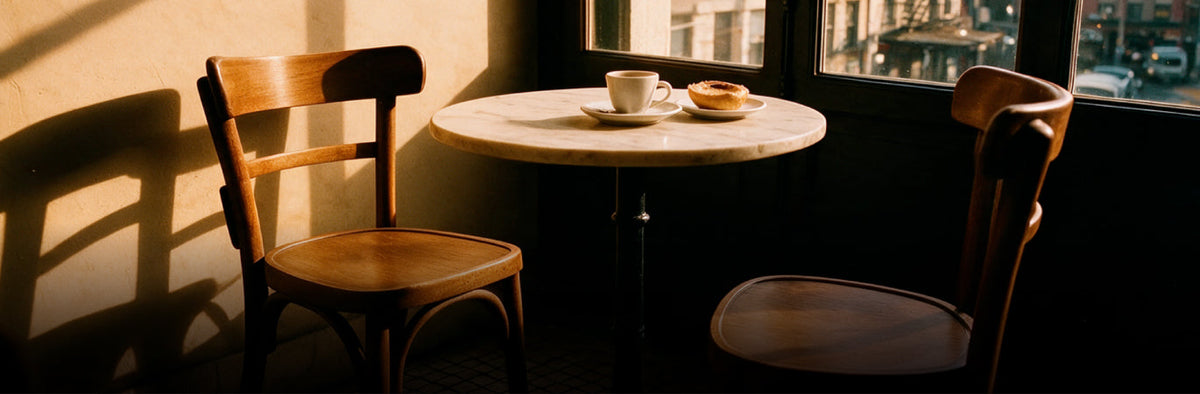 Gourmand menu photo of coffee and a pastry on a cafe table between wooden chairs