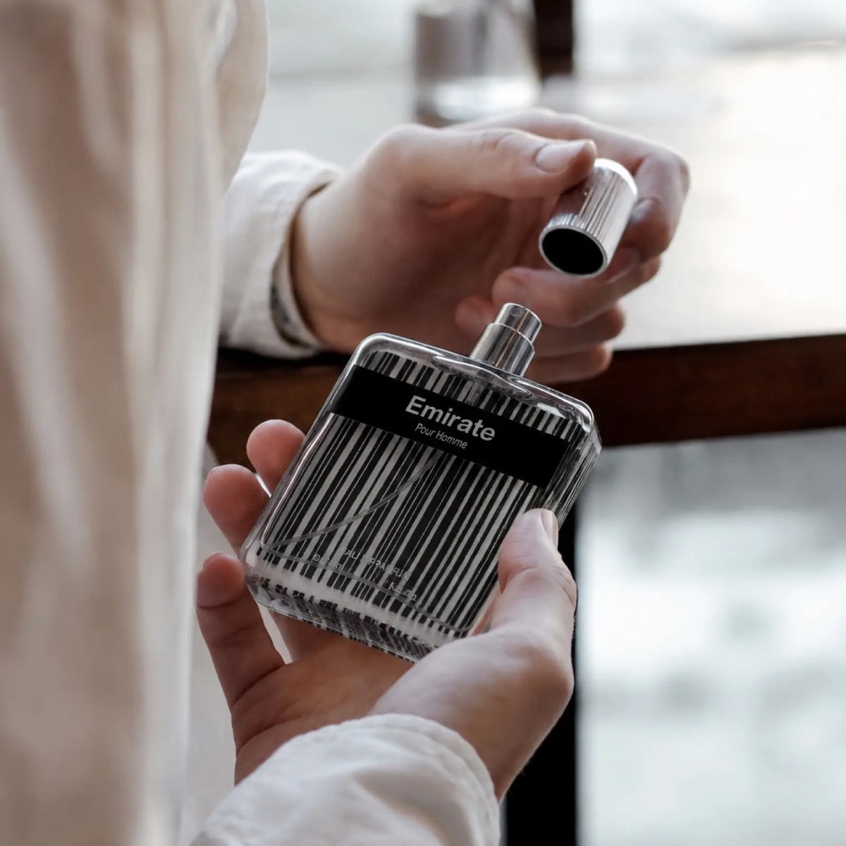 Emirate perfume for men shown in use with the bottle held in hand.