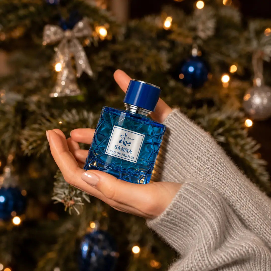 Samma for men and women perfume bottle held in front of a decorated Christmas tree
