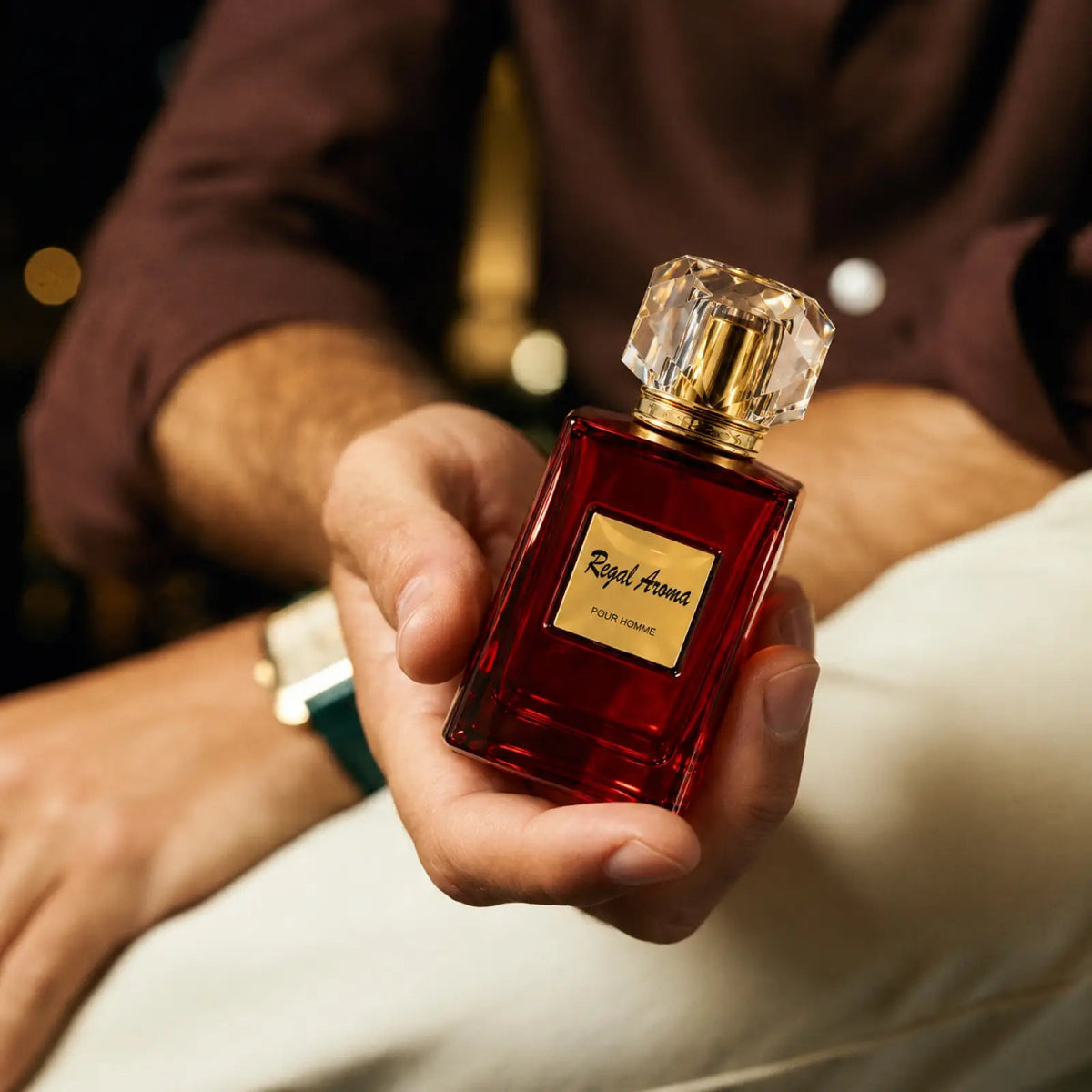 Regal Aroma Pour Homme ruby bottle resting in an open hand