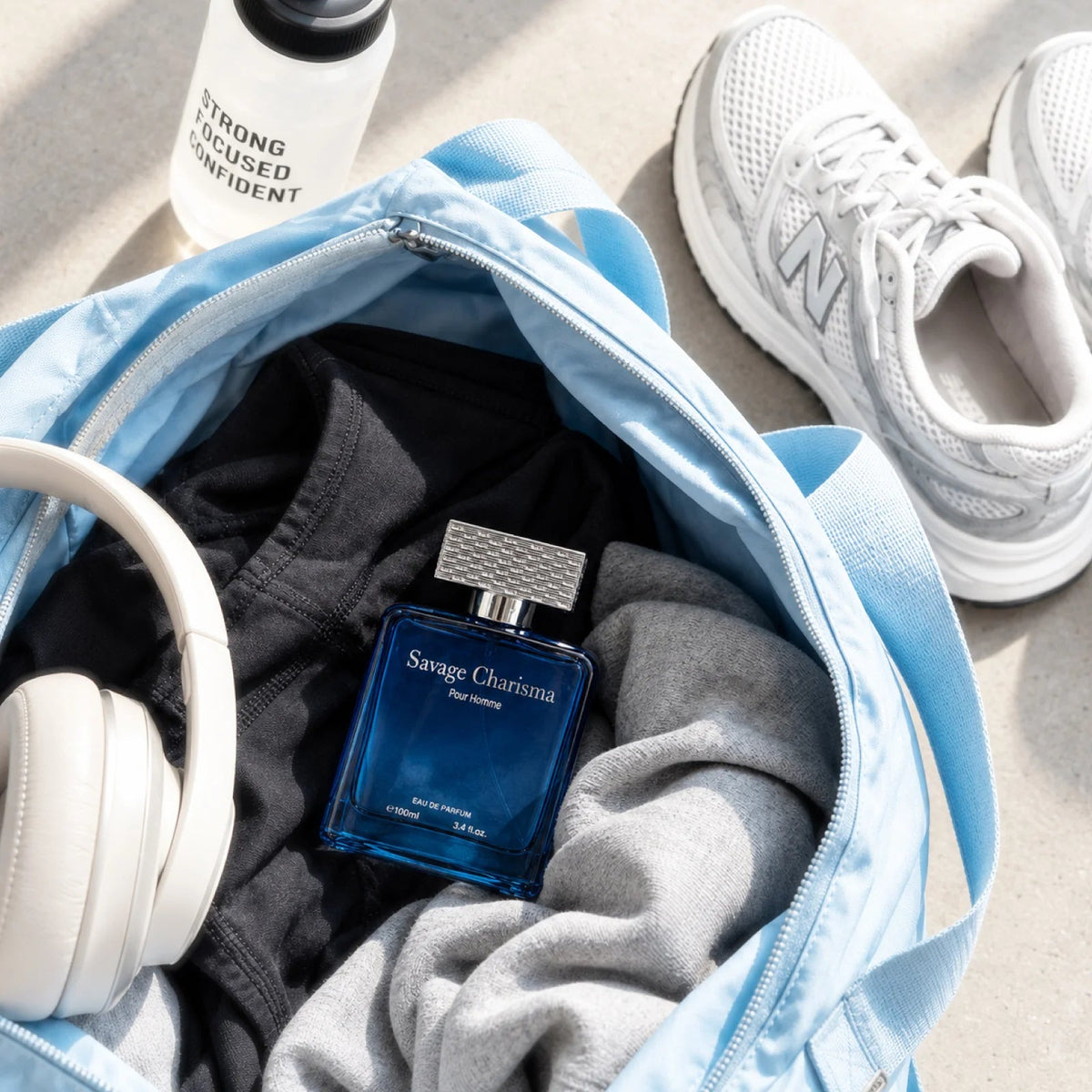 Savage Charisma for men perfume bottle in an open gym bag with clothing and headphones